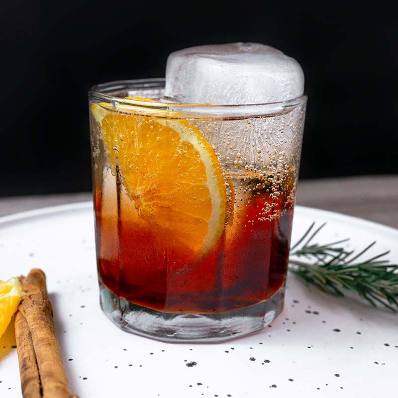 Coffee Negroni in a short glass with a large block of ice and a slice of orange