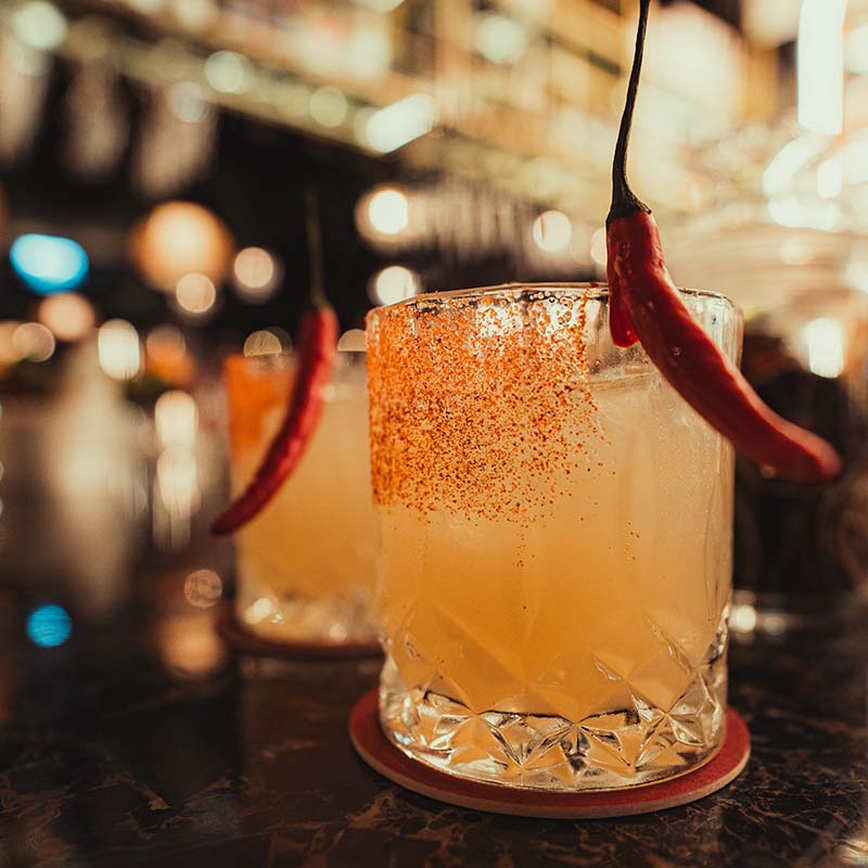 Picante (spiced Margarita) with bright red chilly garnish on a salted glass
